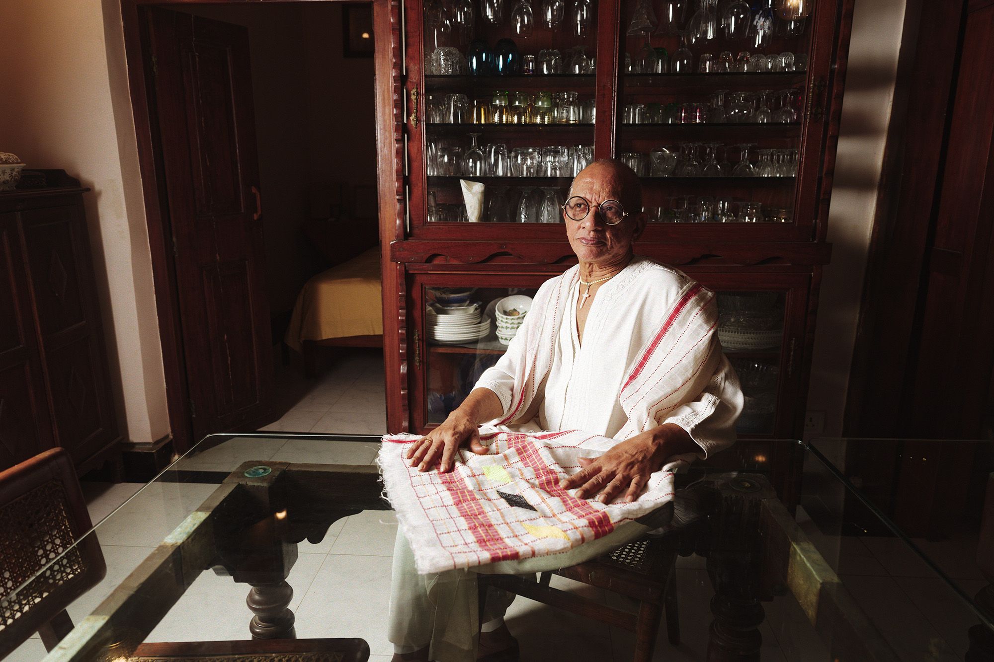 Fashion designer James Ferreira in his dining room wearing a kaftan and an Assamese gamosa