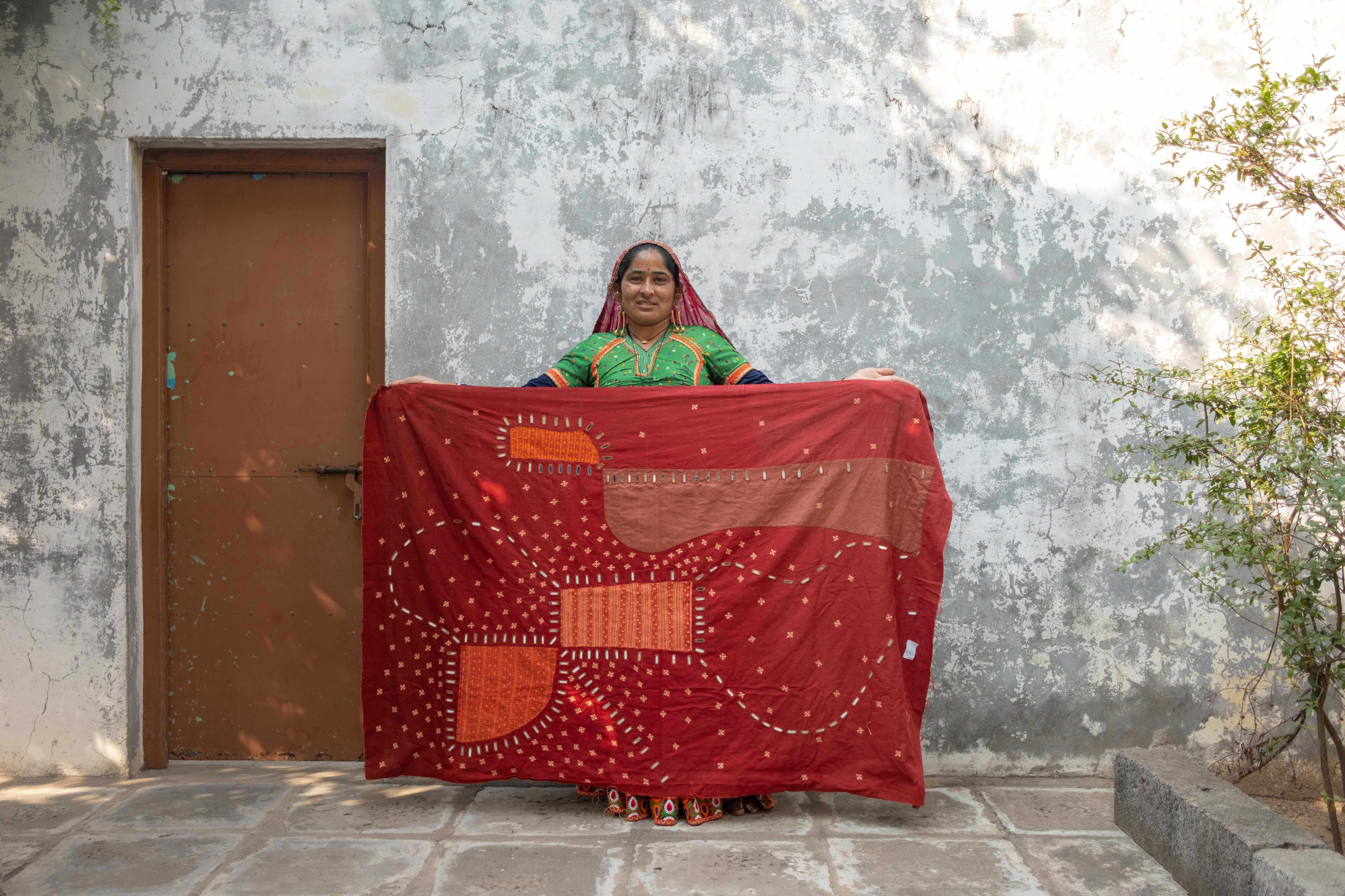 An artisan holding up a Morii Design artwork with Rabari embroidery with mirrors