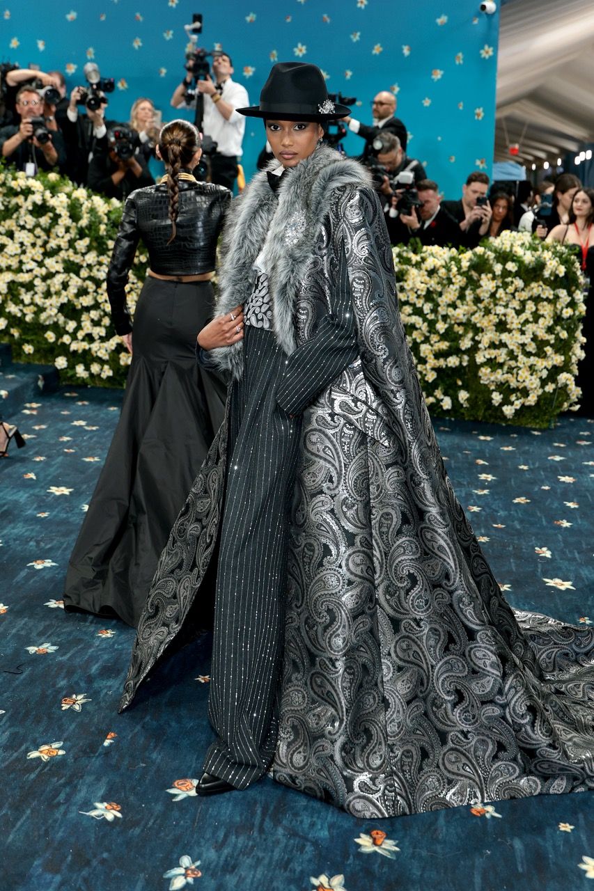 Ugbad Abdi at the 2025 Met Gala in a pewter and paisley brocade cape and suit by Michael Kors Collection